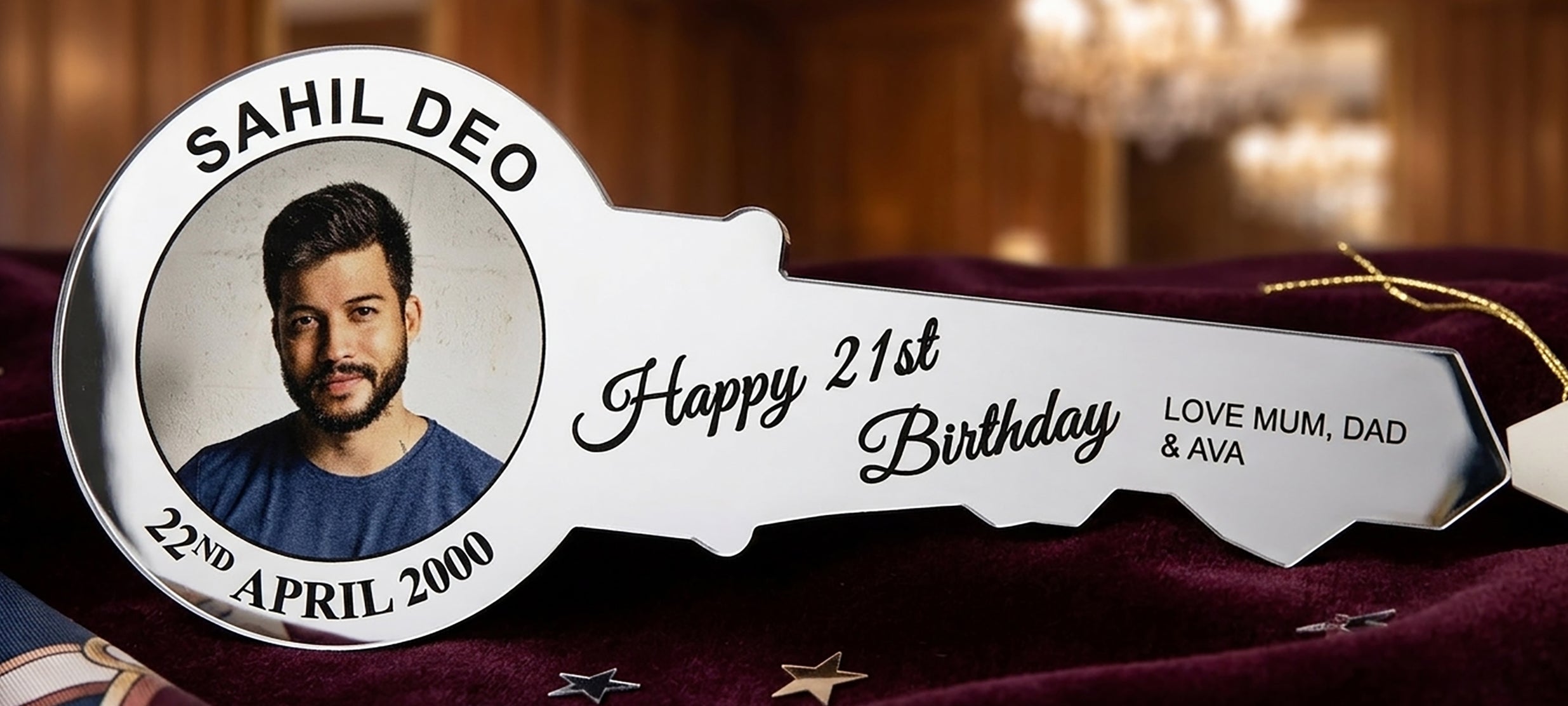 Personalized key-shaped plaque with a photo of a man and birthday details on a red fabric background. silver mirror acrylic
